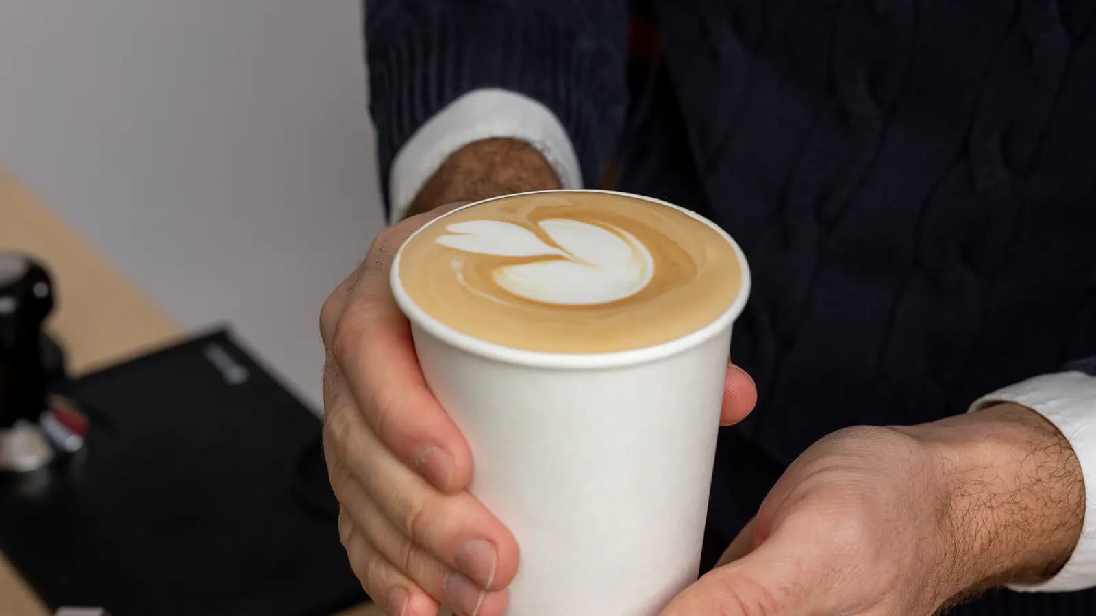 A wide view of a barista pouring latte art.