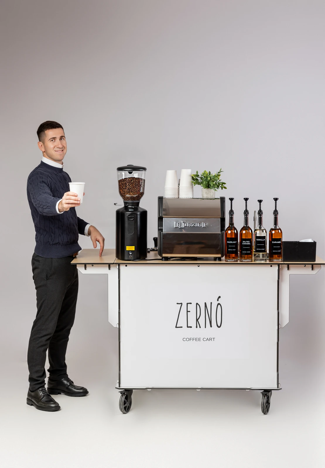 Zerno barista standing beside the coffee cart holding a finished specialty drink